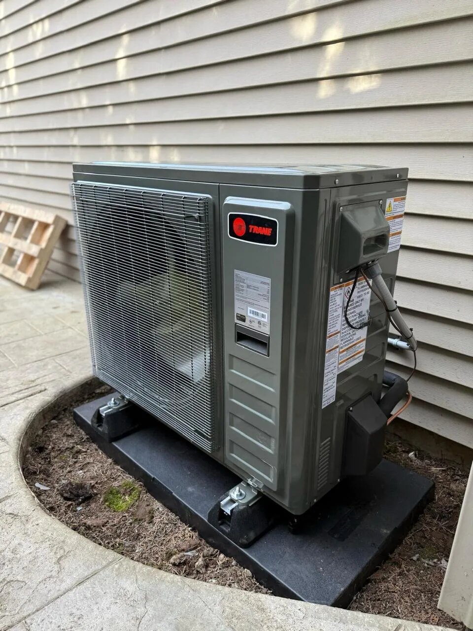 Outdoor heat pump on a pad beside the house